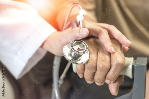 Geriatric doctor or geriatrician concept. Doctor physician hand on happy elderly senior patient to comfort in hospital examination room or hospice nursing home or wellbeing county.