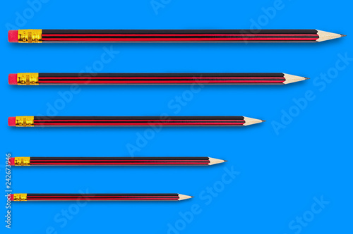 Row of new wooden graphite pencils with rubber eraser tip on blue background from small to large