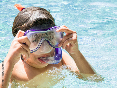 Teenager boy wearing mask swimming in the pool. Happy holiday sunlight concept.