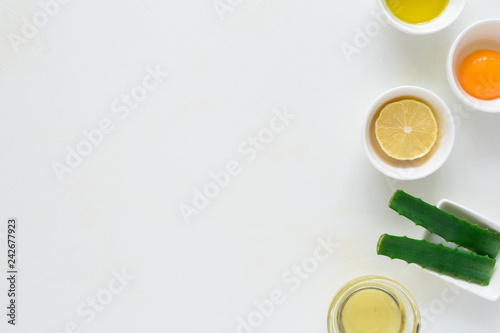 Fresh ingredients for homemade effective acne remedies on white background. Honey  sea salt  egg yolk  olive oil  oat  lemon and aloe. Flat lay. Copy space