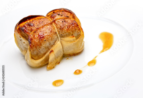 Paupiettes of veal put on a white plate with sauce on the side.