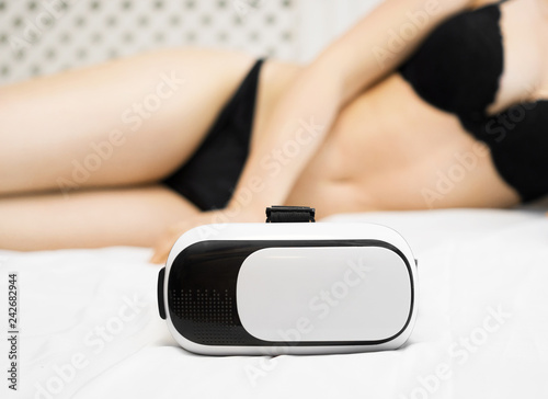 Virtual sex concept. VR glasses and woman on the bed.