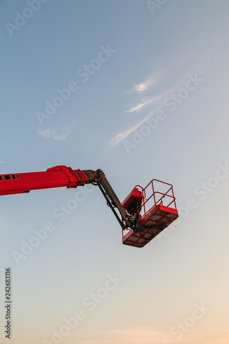 Red bucket crane mounted on truck.Truck mounted Articulating boom lift reaching high up.