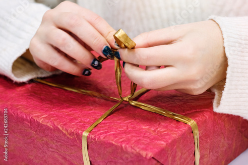 Female hands tie a gift tape of a red box