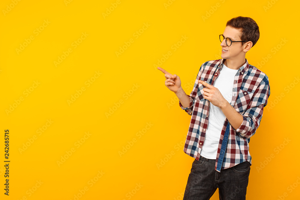 man, wearing glasses, pointing with two fingers to the side, pointing to an empty space, on a yellow background man, wearing glasses, pointing with two fingers to the side, pointing to an empty space, on a yellow background