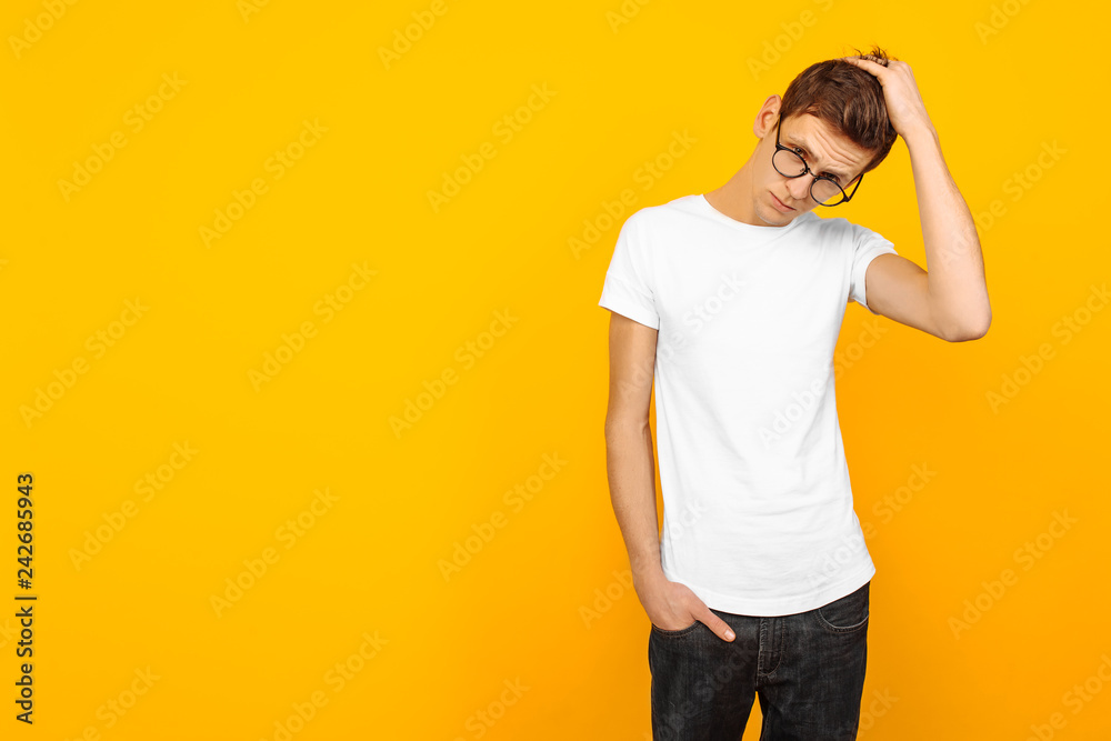 Handsome man in glasses, dressed in a white T-shirt, posing on a yellow background Handsome man in glasses, dressed in a white T-shirt, posing on a yellow background