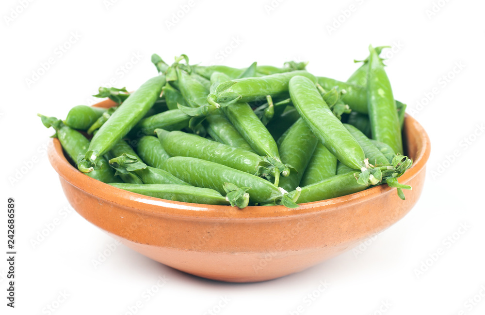 green peas in pods. in a clay plate on a white background green peas in pods. in a clay plate on a white background