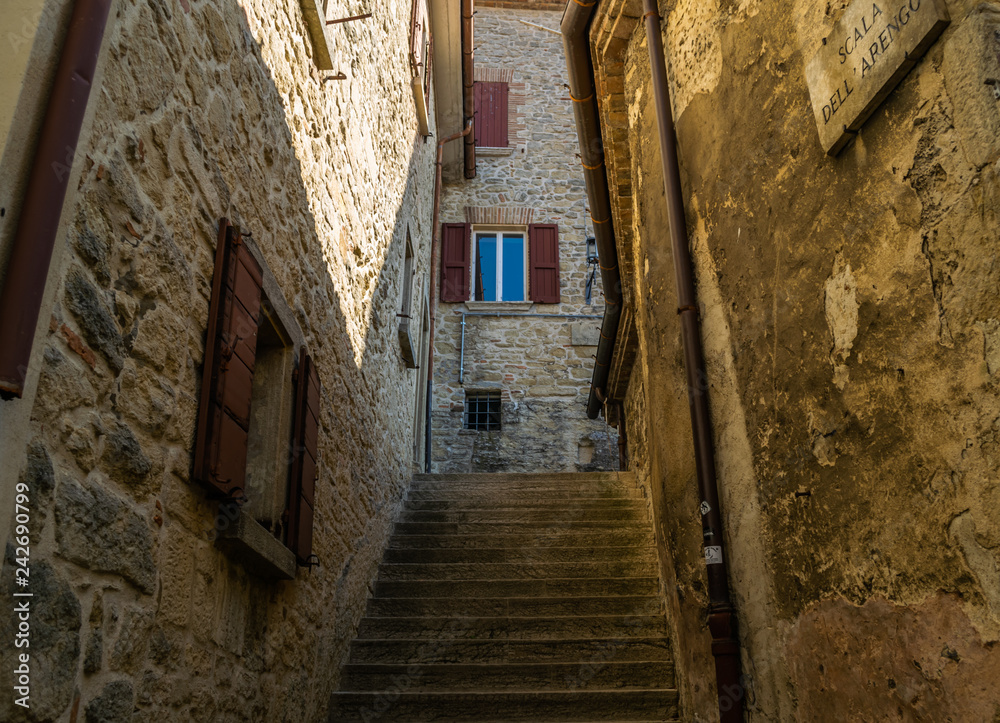 narrow street with old stone fasades and stairs in historical center of san marino city