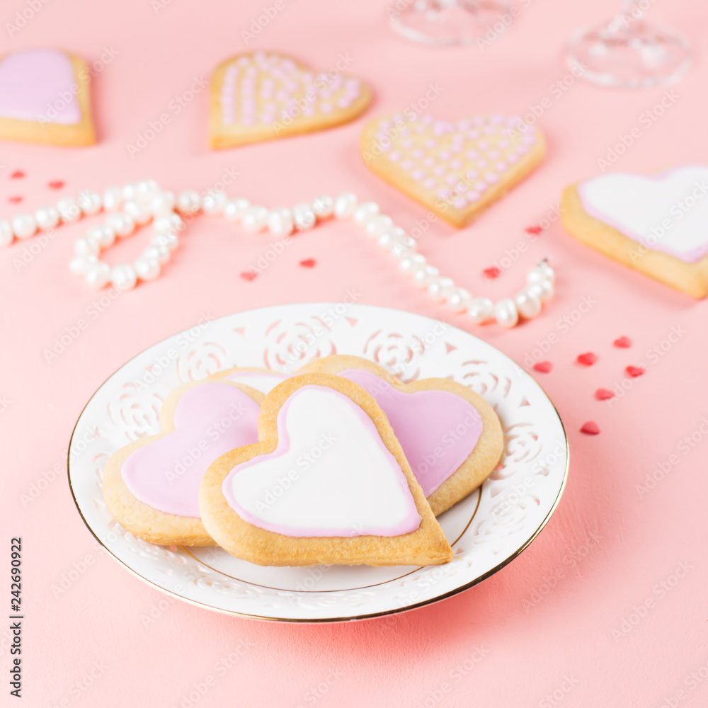 Happy Valentine's day greeting card with heart cookies, wine glasses and wine on pastel pink background.