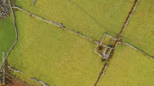 Overhead aerial view of green fields with old stone house ruin in North Wales