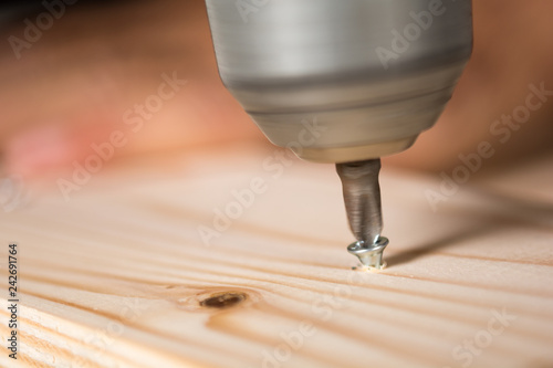 Screwing a screw on a wood with an electric drill bit