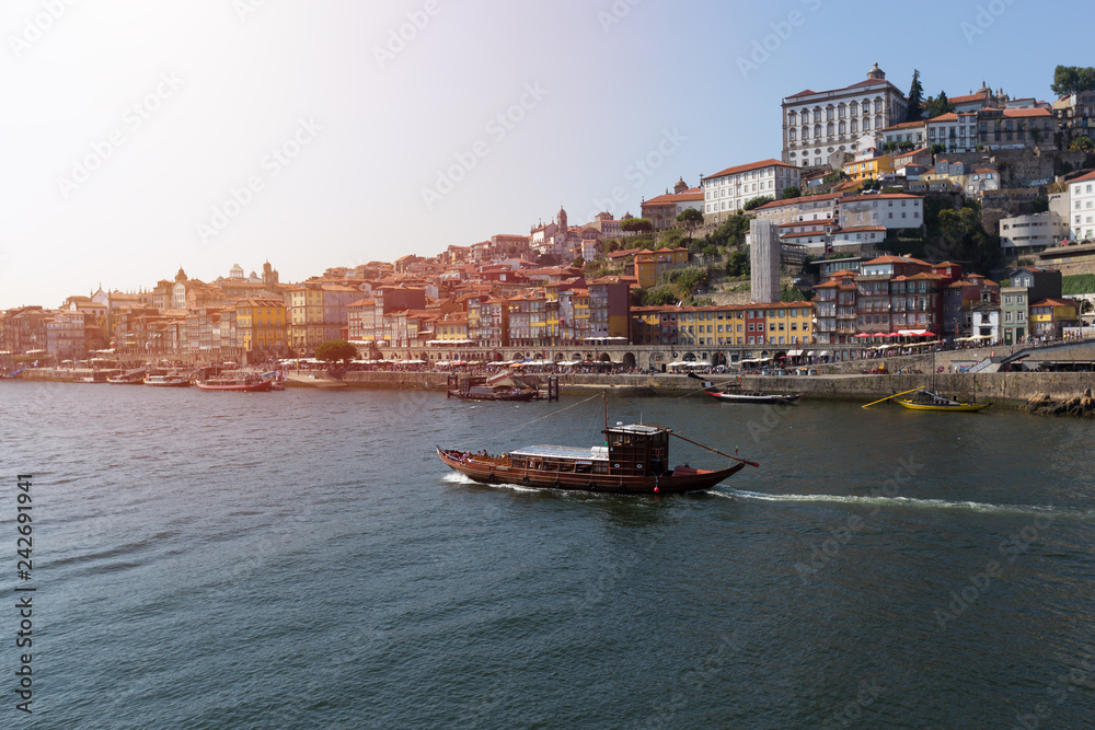 Obraz premium The old town of Porto, and the river Douro, Portugal. Wooden old boat moving by river