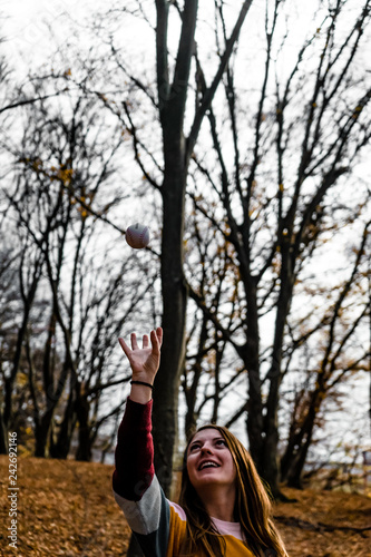 Girl having fun outside with a small ball in the forest