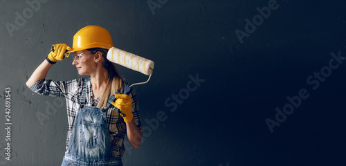 Obraz na płótnie a strong-willed woman in a construction helmet, mittens, goggles and overalls is engaged in repair and construction work at home. concept of a strong and independent woman w salonie