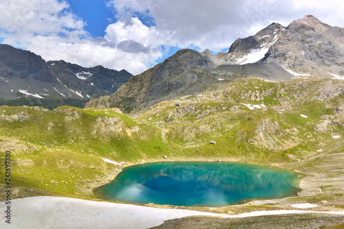 view on a blue lake in alpine mountain under cloudy sky