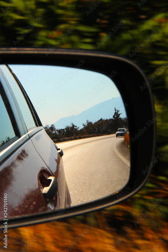 Reflection in the side mirror of the car on a bright day on the road in Greece