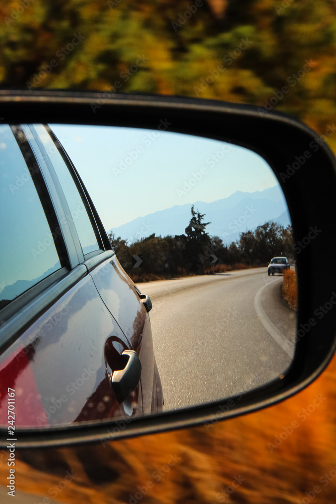 Reflection in the side mirror of the car on a bright day on the road in Greece