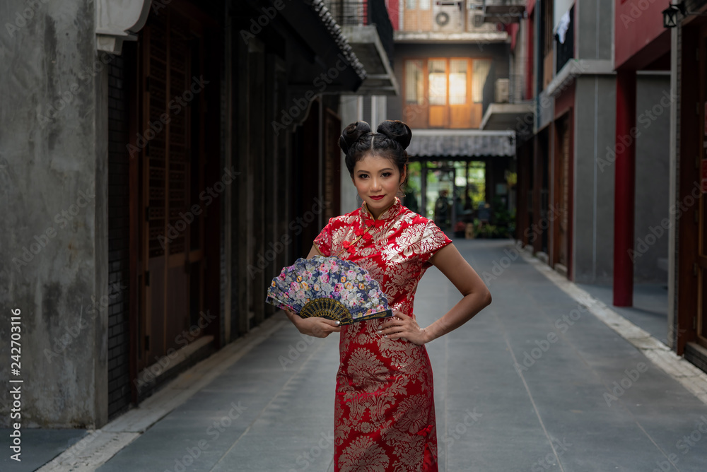 Portrait images pretty Chinese girl Wearing a red Cheongsam dress Holding a Folding fan Welcome Chinese New Year Festival.