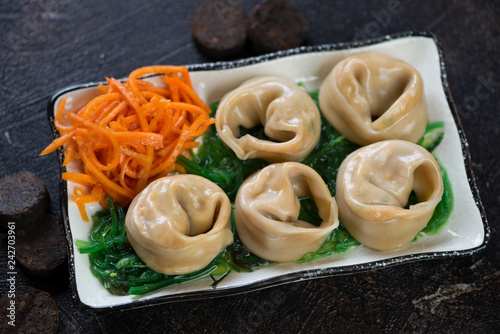 Steamed asian dumplings with salmon, seaweed salad and carrot, studio shot