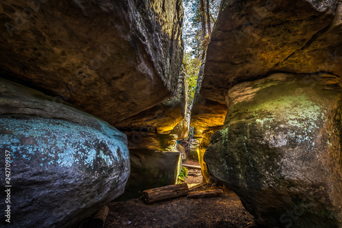 Narrow passage between big rocks in stone labyrinth Bledne skaly, Szczeliniec Wielki in National Park Stolowe Mountains, Poland photo