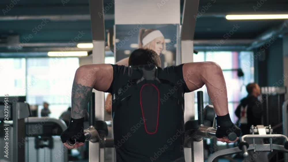 man wringing out on bars in gym, rear view