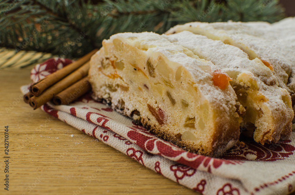 Christmas stollen on darkfestive background with fir twigs, lights and and berries. Close-up on this traditional German dessert Christmas stollen on darkfestive background with fir twigs, lights and and berries. Close-up on this traditional German dessert