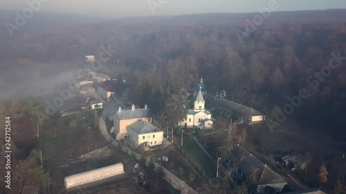 Aerial view of christian monastery surrounded by forest and covered with fog. Thiganesty monastery. Moldova republic of. photo