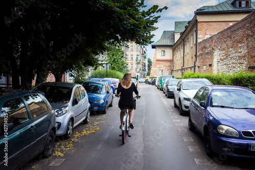 Young and happy woman tourist riding a bike on streets of old european city in Krakow, Poland. Travels around the Europe