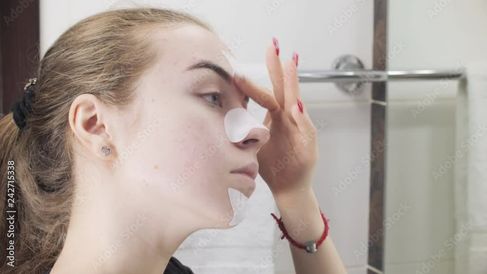 Teen girl applying pore strip on nose, chin, forehead. Clean Pores Teen girl applying pore strip on nose, chin, forehead. Clean Pores