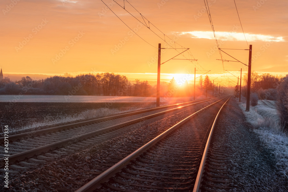 Railroad tracks at sunrise in winter.  Travel context. Industrial landscape.