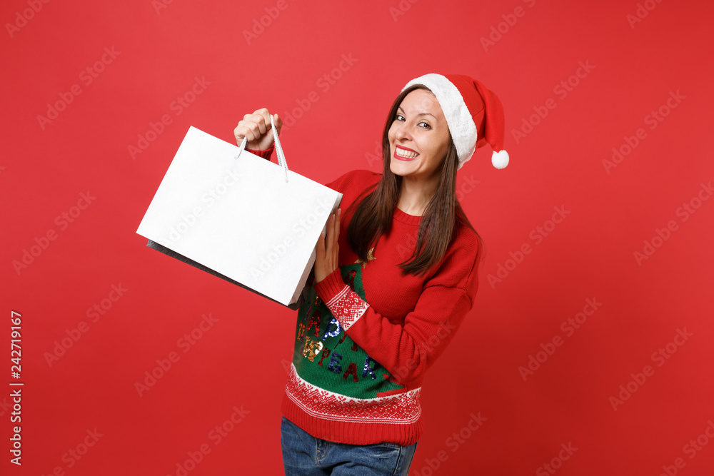 Beautiful joyful young Santa girl holding packages bags with purchases after shopping isolated on bright red wall background. Happy New Year 2019 celebration holiday party concept. Mock up copy space. Beautiful joyful young Santa girl holding packages bags with purchases after shopping isolated on bright red wall background. Happy New Year 2019 celebration holiday party concept. Mock up copy space.
