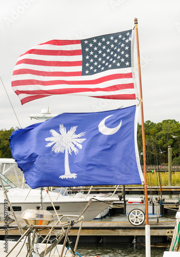 USA Flag and South Carolina State Flag fly together, unfurled, on the same flagpole in the wind at a Hilton Head Island Dock, USA.