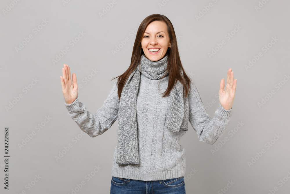Young girl in gray sweater scarf gesturing demonstrating size with horizontal workspace isolated on grey background. Healthy fashion lifestyle people emotions cold season concept. Mock up copy space. Young girl in gray sweater scarf gesturing demonstrating size with horizontal workspace isolated on grey background. Healthy fashion lifestyle people emotions cold season concept. Mock up copy space.