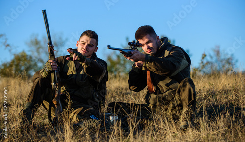 Rest for real men concept. Discussing catch. Hunters with rifles relaxing in nature environment. Hunter friend enjoy leisure in field. Hunting with friends hobby leisure. Hunters gamekeepers relaxing