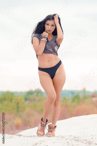 Beautiful sensual black haired woman in safety boots on sand dunes