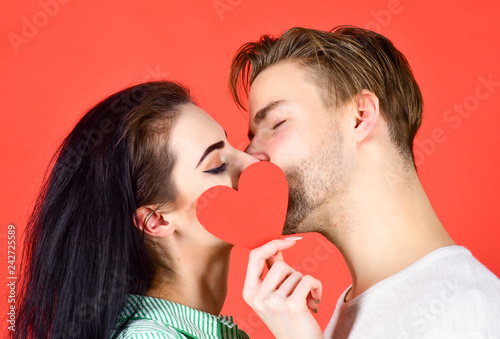 Love and foreplay. Romantic kiss concept. Couple in love kissing and hide lips behind heart card. Celebrate valentines day. Sensual kiss of lovely couple close up. Man and woman romantic kiss