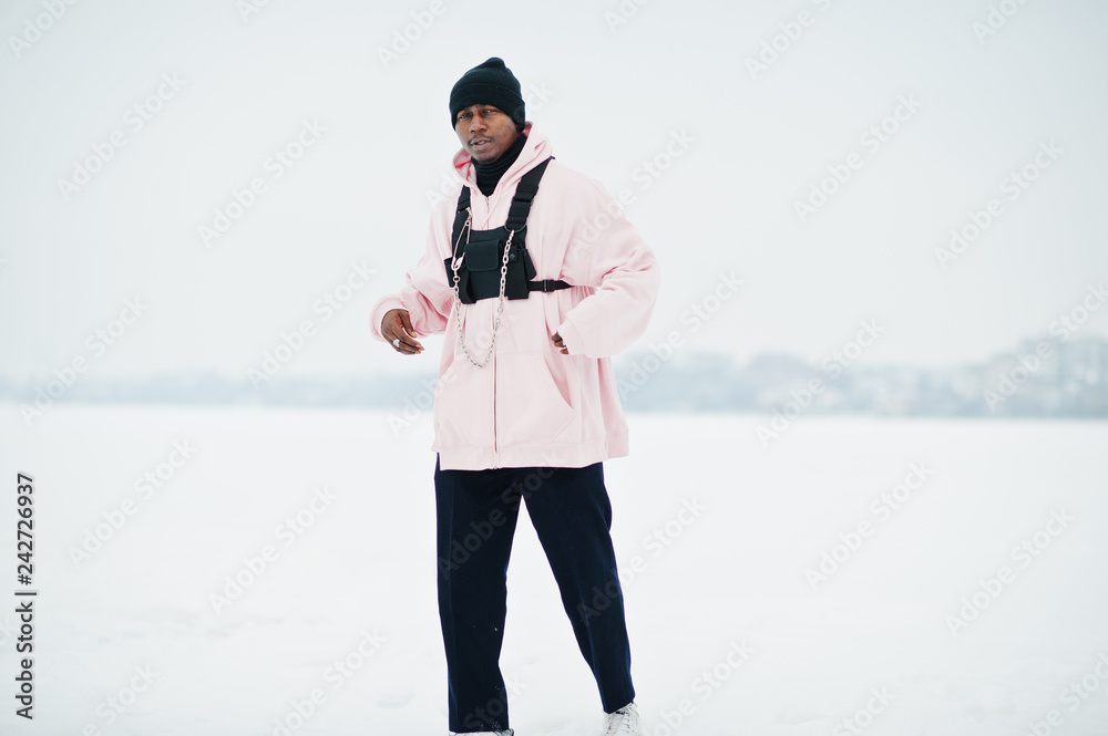 Stylish urban style african american man in pink hoodie posed at frozen lake in winter. Stylish urban style african american man in pink hoodie posed at frozen lake in winter.