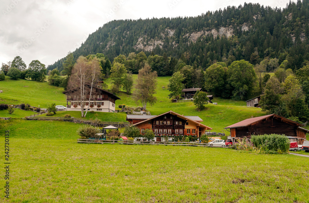 Mountains in Switzerland with wooden houses on a cloudy day