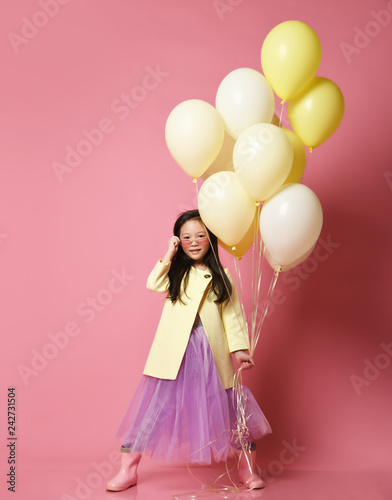Little Korean baby girl in yellow fashion jacket and purple dress with balloons celebrate happy smiling