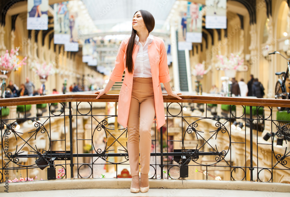 Young brunette woman in beige trousers and in a pink jacket