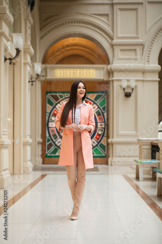 Young brunette woman in beige trousers and in a pink jacket © Andrey_Arkusha