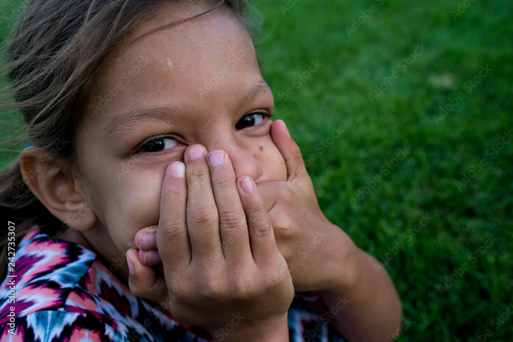 Portrait of girl covering her mouth with hands outdoors Portrait of girl covering her mouth with hands outdoors