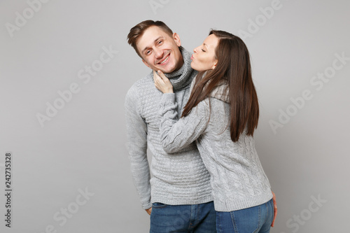 Young cute couple girl guy in gray sweaters, scarves together isolated on grey wall background, studio portrait. Healthy lifestyle, ill sick disease treatment, cold season concept. Mock up copy space. © ViDi Studio