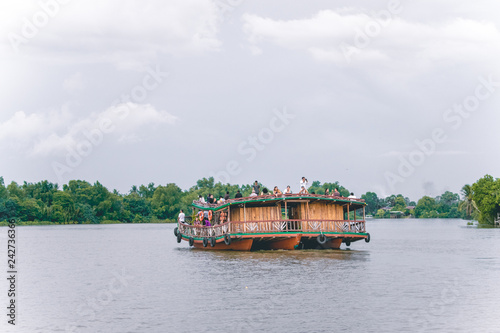 Boat tour on the river near Kampot in Cambodia passing party boats and river bungalows palm trees and fishing boats