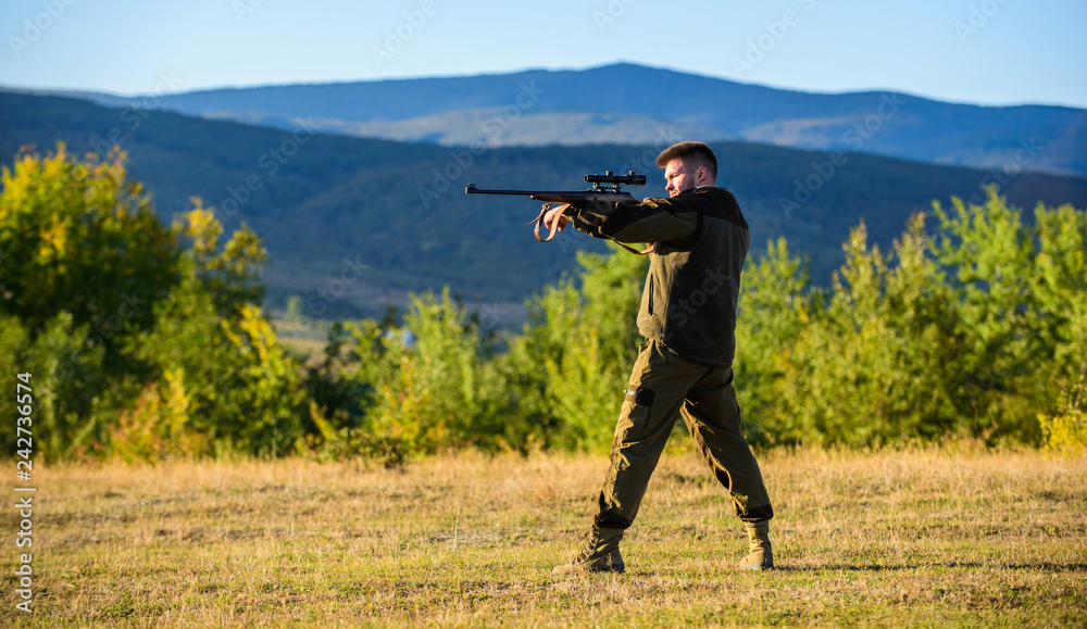 Hunter with rifle looking for animal. Hunting shooting trophy. Man rifle for hunt. Mental preparation for hunting individual process. Hunter khaki clothes ready to hunt hold gun mountains background Hunter with rifle looking for animal. Hunting shooting trophy. Man rifle for hunt. Mental preparation for hunting individual process. Hunter khaki clothes ready to hunt hold gun mountains background