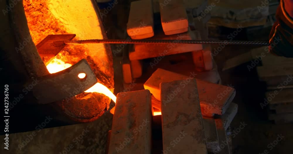 Male worker pouring molten metal in mold at workshop Male worker pouring molten metal in mold at workshop