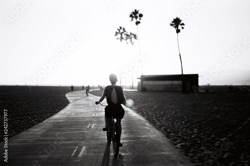 Rear view of woman cycling on road against sky