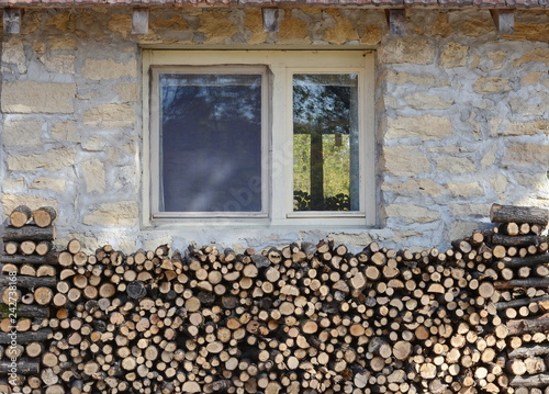 stone mountain house and sorted firewood below the window ready to use for heating. photo