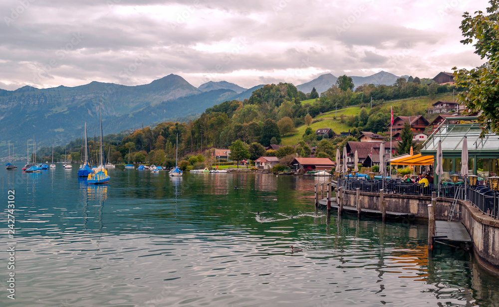 SPIEZ, BERNE, SWITZERLAND-SEPTEMBER 2014, Lake in Switzerland with boats on a cloudy day with mountains in the background