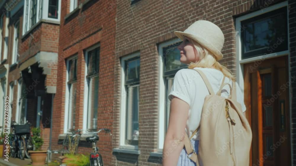 A young woman emotionally enjoys walking along the street of the old city in Europe. Vacation and travel around Europe concept. Delft in the Netherlands A young woman emotionally enjoys walking along the street of the old city in Europe. Vacation and travel around Europe concept. Delft in the Netherlands
